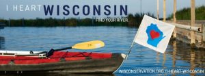 A kayak on the water with a white flag and a blue outline of the state of Wisconsin with a red heart in the center next to a boat launch with text that reads I heart Wisconsin Find your river wisconservation.org/I-Heart-Wisconsin