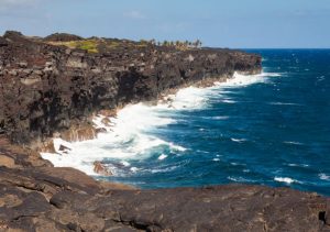 Lava Cliffs on the shoreline of the ocean as waves crash in at Volcanoes National Park