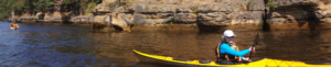 Close up of a kayaker passing a large rock formation