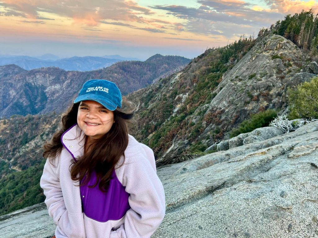 Emma sitting on a rock overlooking the sunrise on the Moro Rock trail in Sequoia National Park
