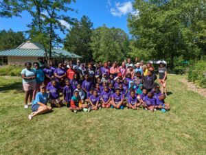 A group of students take a group photo in the grass at Blue Lotus Farm and Retreat Center.