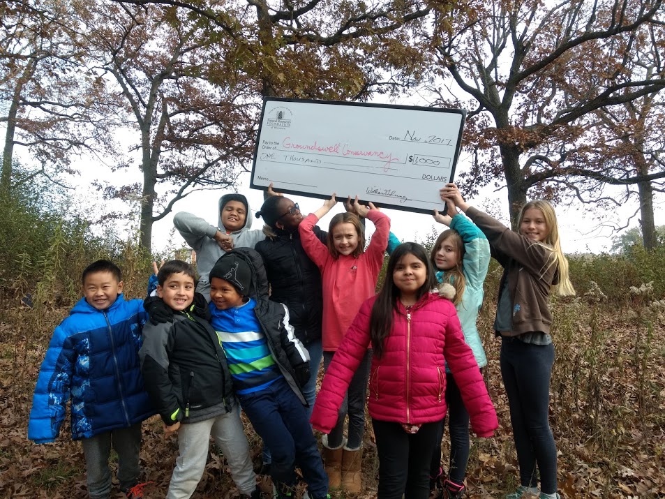 Lake View Elementary students hold up a grant check outside in the woods