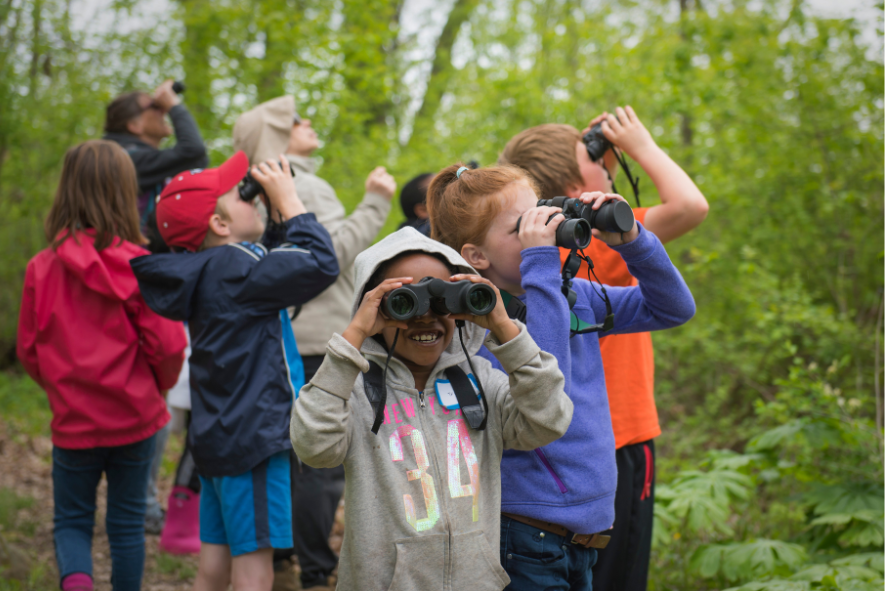 Kids looking through binoculars while outside in the forest; photo for diversity in the outdoors blog