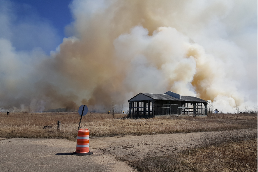 Billowing smoke rising from brown off-season grass, a prescribed fire on Maa Wacacak
