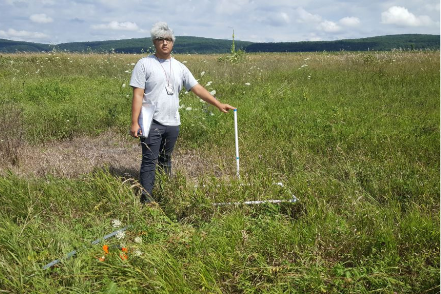 High school student holds a tool used for plant cover estimates