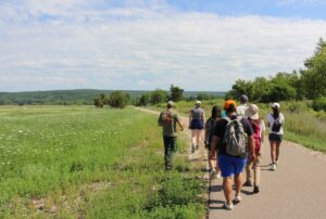 Group of people walking on a paved sidewalk through a field