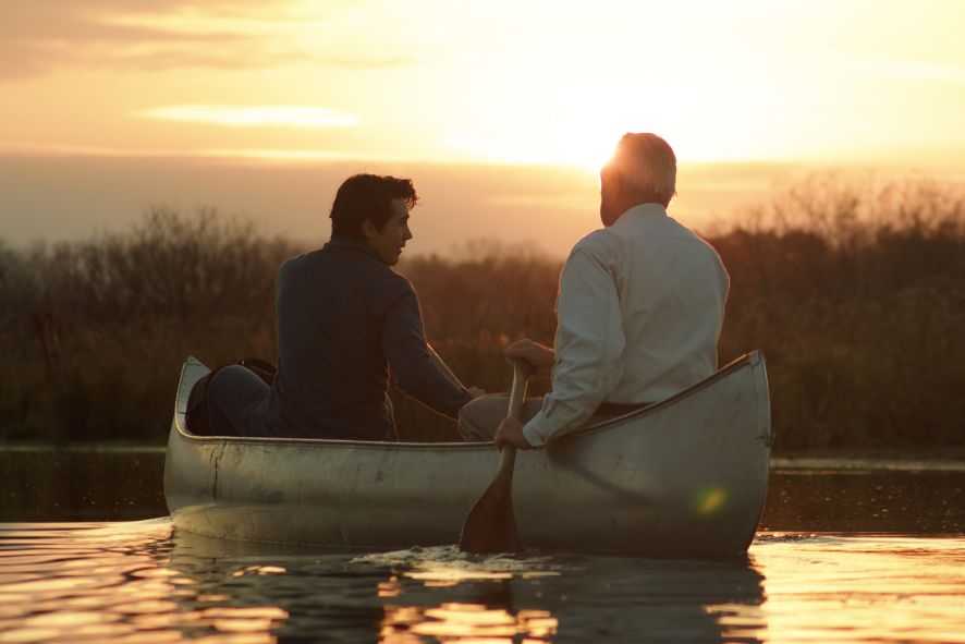 Two people talking while canoeing through wetland at sunset