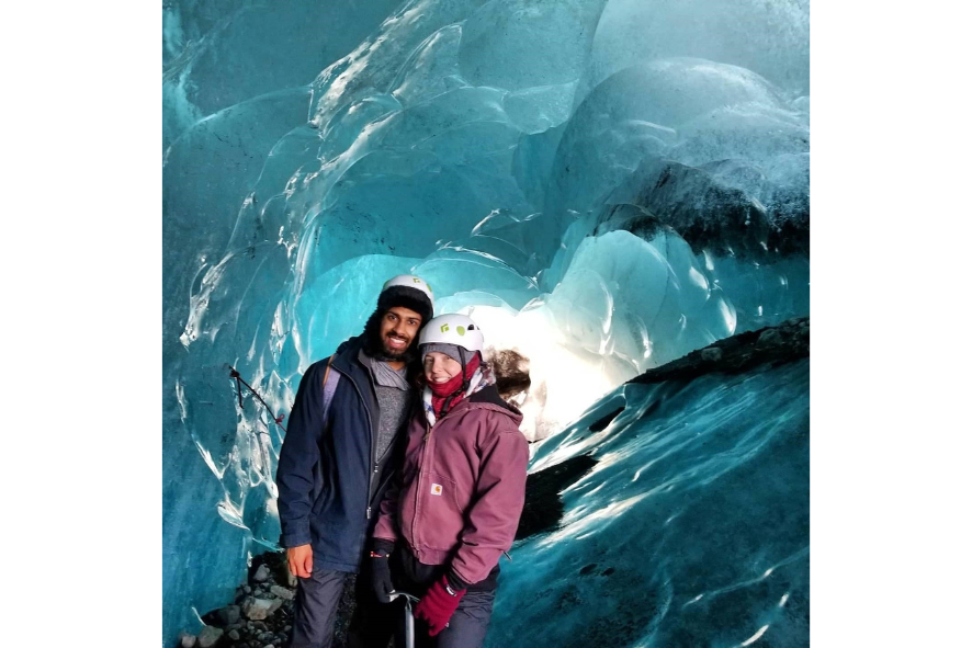 New Executive Assistant,  Michaela and her husband standing in a cave in Iceland. 