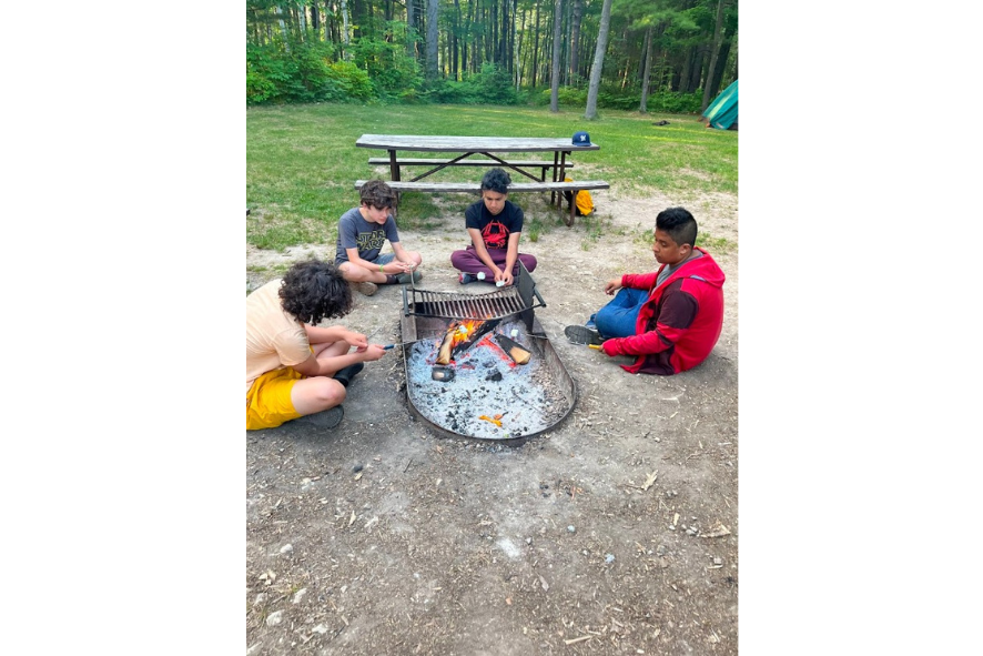 students roasting marshmallows by the fire at camp