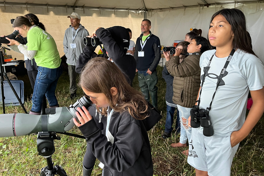 Students birdwatching and looking through a spotting scope.