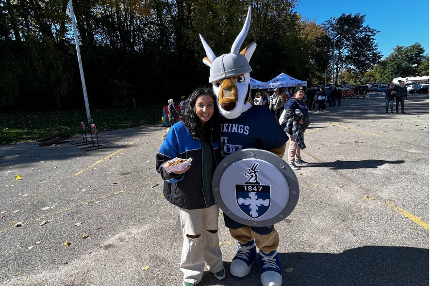 Tee standing in a parking lot with the Lawrence University mascot, an antelope named Blu