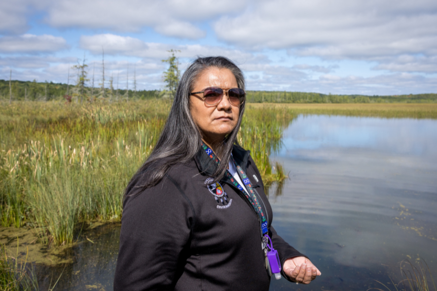 Woman in sunglasses (Tina L. Van Zile) standing on the bank of Spur lake