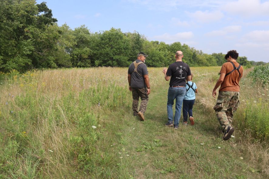 Two adults, a teen, and a child walk a prairie path